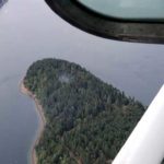 Smoke rises from the site on Ketron Island in Washington state where an Horizon Air turboprop plane crashed Friday after it was stolen from Sea-Tac International Airport as seen from the air, Saturday, Aug. 11, 2018, near Steilacoom, Wash. Investigators were working to find out how an airline employee stole the plane Friday and crashed it after being chased by military jets that were quickly scrambled to intercept the aircraft. (AP Photo/Ted S. Warren)