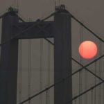 The sun is seen through smoky air as it sets Sunday, Aug. 19, 2018, behind the Narrows Bridge in Tacoma, Wash. Poor air quality will be common across parts of the Pacific Northwest this week as winds push smoke from surrounding wildfires into the region, forecasters and regulators said, and air quality alerts are in effect for much of Washington state through Wednesday. (AP Photo/Ted S. Warren)