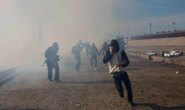 Migrants run from tear gas launched by U.S. agents, amid photojournalists covering the Mexico-U.S. ...
