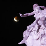 A lunar eclipse progresses behind the "Monumento a la Carta Magna y Las Cuatro Regiones Argentinas" in Buenos Aires, Argentina, Monday, Jan. 21, 2019. It's also the year's first supermoon, when a full moon appears a little bigger and brighter thanks to its slightly closer position to Earth. (AP Photo/Natacha Pisarenko)