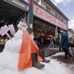   A snow sculpture is dressed as the fish mongers working behind as people walk into the Pike Place Market in near-freezing weather Tuesday, Feb. 5, 2019, in Seattle. Winter weather closed schools and disrupted travel across much of the West, with ice and snow stretching from Seattle to Arizona. The Pacific Northwest shivered Tuesday under colder-than-normal conditions as snow and treacherous conditions led to another day of school closures. (AP Photo/Elaine Thompson)