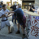 
              A person tries to take away a hammer from a man at left who was using it to remove artwork on barricades Friday, June 26, 2020 at the CHOP (Capitol Hill Occupied Protest) zone in Seattle. The man lives in a house in the same block and said he was tired of protesters occupying his neighborhood. Also on Friday Seattle Department of Transportation workers arrived with the intention of removing barricades that had been set up in the area, but left after being met with resistance from protesters. (AP Photo/Ted S. Warren)
            