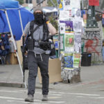 
              A member of the volunteer security team at the Capitol Hill Occupied Protest Zone carries a rifle as he walks Saturday, June 20, 2020, inside the CHOP in Seattle. Armed volunteers said they were patrolling Saturday to keep the area safe. A pre-dawn shooting Saturday near the area left one person dead and critically injured another person, authorities said Saturday. The area has been occupied by protesters after Seattle Police pulled back from several blocks of the city's Capitol Hill neighborhood near the Police Department's East Precinct building. (AP Photo/Ted S. Warren)
            