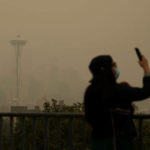 SEATTLE, WA - SEPTEMBER 12:  A woman wears a mask as she takes photos of the smoke-obscured Seattle skyline on September 12, 2020 in Seattle, Washington. According to the National Weather Service, the air quality in Seattle remained at "unhealthy" levels Saturday after a large smoke cloud from wildfires on the West Coast settled over the area. (Photo by Lindsey Wasson/Getty Images)
