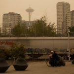 SEATTLE, WA - SEPTEMBER 12:  People wait for a train to cross Alaskan Way near the waterfront as smoke from wildfires fills the air on September 12, 2020 in Seattle, Washington. According to the National Weather Service, the air quality in Seattle remained at "unhealthy" levels Saturday after a large smoke cloud from wildfires on the West Coast settled over the area. (Photo by Lindsey Wasson/Getty Images)