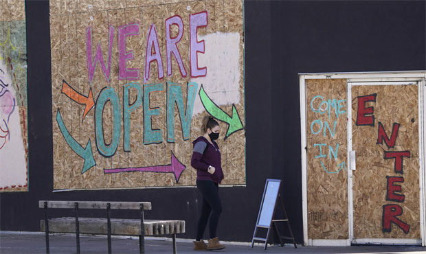 A woman heads into a restaurant with its windows covered by sheets of plywood, one block south of the State Capitol. (AP Photo/David Zalubowski) 