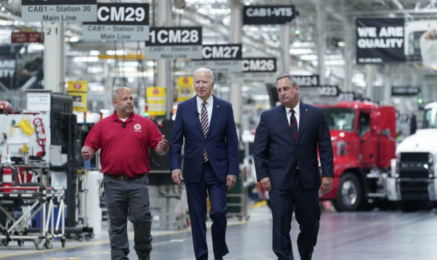 President Joe Biden walks with Mack Trucks President Martin Weissburg, right, and UAW Local 677 Sho...