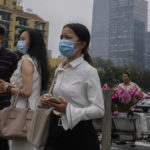 
              People wearing face masks to help curb the spread of the coronavirus stand watch near a vendor selling flowers outside a subway station in Beijing, Thursday, July 22, 2021. A senior Chinese health official says China cannot accept the World Health Organization's plan for the second phase of a study into the origins of COVID-19. (AP Photo/Andy Wong)
            