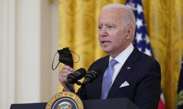 President Joe Biden holds a face mask as he announces from the East Room of the White House in Wash...