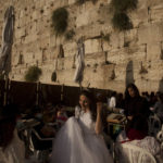 
              A bride leaves after praying and posing for wedding photos at the Western Wall, the holiest site where Jews can pray, in the shadow of the Mughrabi Bridge, a wooden pedestrian bridge connecting the wall to the Al Aqsa Mosque compound, in Jerusalem's Old City, Tuesday, July 20, 2021. The rickety bridge allowing access to Jerusalem's most sensitive holy site is at risk of collapse, according to experts. But the flashpoint shrine's delicate position at ground-zero of the Israeli-Palestinian conflict has prevented its repair for more than a decade. (AP Photo/Maya Alleruzzo)
            