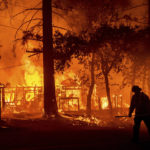 
              A firefighter passes a burning home as the Dixie Fire flares in Plumas County, Calif., Saturday, July 24, 2021. The fire destroyed multiple residences as it tore through the Indian Falls community. (AP Photo/Noah Berger)
            