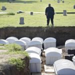
              Graves Public Oversight Committee Chair J. Kavin Ross views remains in a mass grave are reintered at Oaklawn Cemetery, Friday, July 30, 2021, in Tulsa, Okla. The mass grave was discovered while searching for victims of the Tulsa Race Massacre. (Mike Simons/Tulsa World via AP)
            