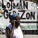 
              A woman speaks on the phone in front of a sign in Haitian Creole during a news conference held by a coalition of housing justice groups to protest evictions, Friday, July 30, 2021, outside the Statehouse in Boston. (AP Photo/Michael Dwyer)
            