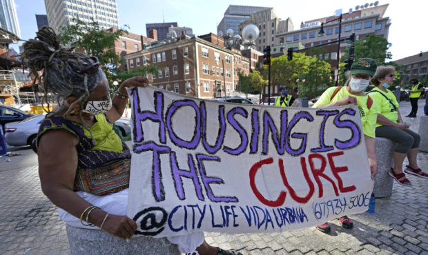 In this June 9, 2021, photo, people hold a sign during a rally in Boston protesting housing evictio...