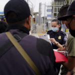 
              FILE - In this July 5, 2021 file photo a United States Customs and Border Protection officer examines paperwork of migrants waiting to cross into the United States to begin the asylum process in Tijuana, Mexico. Two nongovernmental organizations said Friday, July 30, 2021, that they are ending cooperation with the Biden Administration to identify the most vulnerable migrants waiting in Mexico to be admitted to the United States to seek asylum. (AP Photo/Gregory Bull, File)
            