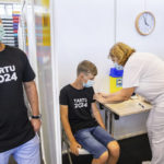 
              A medical worker, right, administers a shot of a coronavirus vaccine to Joonas Leis , 12 years old boy, center, as his father Kuldar stands near at a vaccination center inside a sports hall in Estonia's second largest city, Tartu, 164 km. south-east from Tallinn, Estonia, Thursday, July 29, 2021. Estonia's second largest city Tartu is making rapid progress in vaccinating children aged 12-17 ahead of the school year in September. Around half of the town's teenagers have already received their first vaccine, and local health officials are confident they will hit 70% in the coming 30 days. (AP Photo/Raul Mee)
            