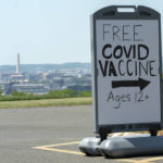 
              FILE - In this Wednesday, May 19, 2021 file photo, downtown Washington and the Washington Monument are seen behind a sign adverting a free vaccine drive with Pfizer COVID-19 vaccinations for members of the community 12 years and up outside a school in southeast Washington. On Friday, July 16, 2021, The Associated Press reported on stories circulating online incorrectly asserting President Joe Biden’s administration introduced a door-to-door campaign to offer COVID-19 vaccines as a way to confiscate guns or Bibles. But the vaccine campaign does not involve federal workers, it relies on local officials, private sector workers and volunteers to go into areas where there are lower vaccination rates and provide information on where to access the vaccine. (AP Photo/Jacquelyn Martin, File)
            