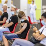 
              Joonas Leis , 12 years old boy, center, as his father Kuldar, left of him, rest after getting a shot a coronavirus vaccine at a vaccination center inside a sports hall in Estonia's second largest city, Tartu, 164 km. south-east from Tallinn, Estonia, Thursday, July 29, 2021. Estonia's second largest city Tartu is making rapid progress in vaccinating children aged 12-17 ahead of the school year in September. Around half of the town's teenagers have already received their first vaccine, and local health officials are confident they will hit 70% in the coming 30 days. (AP Photo/Raul Mee)
            