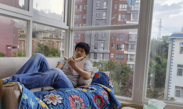 In this photo released by Guo Jianlong, Guo reads a book at the balcony of his home in Dali in sout...