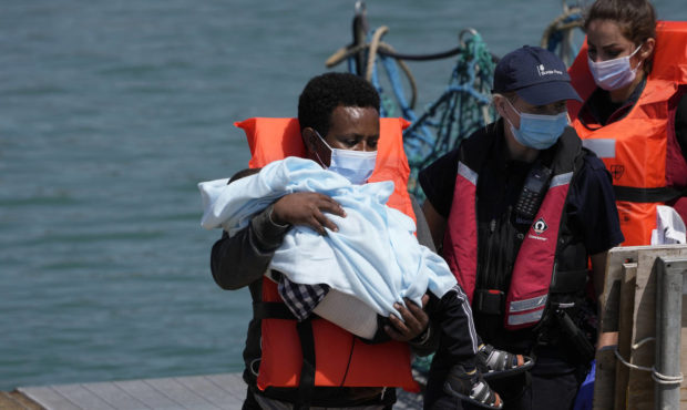 A man and a child thought to be migrants are disembarked from a British border force vessel in Dove...