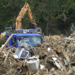 
              Heavy machinery helps sort debris at a temporary storage area, after devastating floods near Kreuzberg, Germany, Monday July 26, 2021.  Recent heavy rains caused deadly floods across the region, with some thousands of people displaced as towns and villages were inundated. (Thomas Frey/dpa via AP)
            