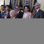 
              President Joe Biden hands out a pen after signing an executive order aimed at promoting competition in the economy, in the State Dining Room of the White House, Friday, July 9, 2021, in Washington. Standing from left, Transportation Secretary Pete Buttigieg, Lina Khan, Chair of the Federal Trade Commission, Health and Human Services Secretary Xavier Becerra, Commerce Secretary Gina Raimondo, Attorney General Merrick Garland, National Economic Council director Brian Deese, obscured, and Jessica Rosenworcel, Acting Chairwoman of the Federal Communications Commission. (AP Photo/Evan Vucci)
            