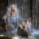 
              Israeli Arabs stand under a waterfall during the Muslim Eid al-Adha holiday at the Gan HaShlosha national park near the northern Israeli town of Beit Shean, Wednesday, July 21, 2021. Eid al-Adha meaning "Feast of Sacrifice," this most important Islamic holiday marks the willingness of the Prophet Ibrahim (Abraham to Christians and Jews) to sacrifice his son.  (AP Photo/Oded Balilty)
            