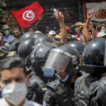 
              Protesters face Tunisian police officers during a demonstration in Tunis, Tunisia, Sunday, July 25, 2021. Violent demonstrations broke out on Sunday in several Tunisian cities as protesters expressed anger at the deterioration of the country's health, economic and social situation. (AP Photo/Hassene Dridi)
            