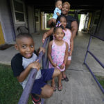 
              Brianne Epps of Jackson, Miss., 28, background, is a single mother with sons Micah Epps, 4, in front, and Nolan Epps, 11 months in her arms and daughters Laila Barnes, 6, second from left, and Kaylee Barnes, 8, center, outside her apartment complex in Jackson, Miss., Wednesday, July 21, 2021. Epps earns $9 an hour working with infants and toddlers in a childcare center, but she has a bigger dream of operating a soul food catering business. (AP Photo/Rogelio V. Solis)
            