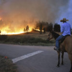 
              Rowdy Alexander watches from atop his horse as a hillside burns on the Northern Cheyenne Indian Reservation, Wednesday, Aug 11, 2021, near Lame Deer, Mont. The Richard Spring fire was threatening hundreds of homes as it burned across the reservation. (AP Photo/Matthew Brown)
            