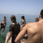 
              People jump in the sea at a beach of Kavouri suburb, southwest of Athens, on Friday, July 30, 2021. Greek authorities ordered additional fire patrols and infrastructure maintenance inspections Friday as the country grappled with a heat wave expected to last more than a week, with temperatures expected to reach 42 C (107.6 F). (AP Photo/Yorgos Karahalis)
            
