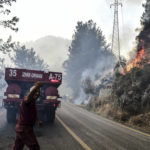 
              Firefighters work as the wildfires engulf an area near the seashore, forcing people to be evacuated by boats, in Bodrum, Mugla, Turkey, Sunday, Aug. 1, 2021. Wildfires in the Turkish holiday destinations of Antalya and Mugla are still raging as firefighters worked to battle the blazes for a fifth day. Authorities warned tourists and residents to keep evacuating Turunc, a town in the seaside resort of Marmaris, and navy ships waited in the sea there to see if a bigger evacuation was needed. (Ismail Coskun/IHA via AP)
            