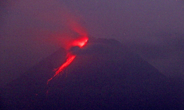 In this photo taken using slow camera shutter speed, hot lava runs down from the crater of Mount Me...