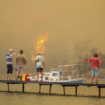 
              Tourists wait to be evacuated from smoke-engulfed Mazi area as wildfires rolled down the hill toward the seashore, in Bodrum, Mugla, Turkey, Sunday, Aug. 1, 2021. More than 100 wildfires have been brought under control in Turkey, according to officials. The forestry minister tweeted that five fires are continuing in the tourist destinations of Antalya and Mugla. (AP Photo/Emre Tazegul)
            