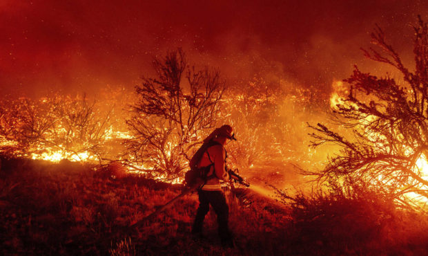 FILE - In this Aug. 16, 2021, file photo, a firefighter battles the Dixie Fire as it jumps Highway ...