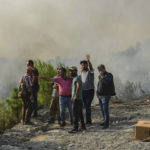 
              People watch the wildfires that continue to rage the forests in Manavgat, Antalya, Turkey, early Sunday, Aug. 1, 2021. The fires in Antalya were continuing overnight in Manavgat and Gundogmus districts. In Bodrum, Mugla, they continued to burn down forests, encroaching on villages and tourist destinations and forcing people to evacuate by boats. (AP Photo)
            
