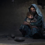 
              Sarab village resident Raihan comforts her 1-year-old son after having an early morning opium smoke with family members in the Badakhshan province of Afghanistan, July 13, 2009. Raihan was addicted to opium while pregnant with her son making him an addict at birth. "When he was born, he would cry day and night. But when she blows smoke in his face, he sleeps," said her father Islam Beg. In dozens of mountain hamlets in this remote corner of Afghanistan, opium addiction has become so entrenched that whole families, from toddlers to old men, are addicts. (AP Photo/Julie Jacobson)
            