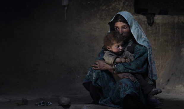 Sarab village resident Raihan comforts her 1-year-old son after having an early morning opium smoke...