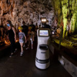 
              Persephone guides the visitors inside Alistrati cave, about 135 kilometers (84 miles) northeast of Thessaloniki, Greece, Monday, Aug. 2, 2021. Persephone, billed as the world's first robot used as a tour guide inside a cave, has been welcoming visitors to the Alistrati cave, since mid-July. (AP Photo/Giannis Papanikos)
            