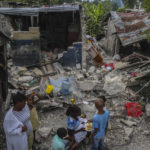 
              A family eats breakfast in front of homes destroyed by a 7.2 magnitude earthquake in Les Cayes, Haiti, Sunday, Aug. 15, 2021. (AP Photo/Joseph Odelyn)
            