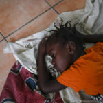
              A girl sleeps inside a church sheltering earthquake-displaced people the morning after Tropical Storm Grace swept over Les Cayes, Haiti, Tuesday, Aug. 17, 2021, three days after a 7.2 magnitude quake. (AP Photo/Matias Delacroix)
            