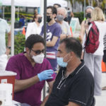 
              Carlos Anacleto closes his eyes as he receives the Pfizer COVID-19 vaccine from nurse Jorge Tase, as others wait their turn, Wednesday, Aug. 4, 2021, in Miami Beach, Fla. On Tuesday, the CDC added more than 50,000 new COVID-19 cases in the state over the previous three days, pushing the seven-day average to one the highest counts since the pandemic began, an eightfold increase since July 4. (AP Photo/Marta Lavandier)
            