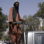 
              A Taliban fighter sits on the back of vehicle with a machine gun in front of the main gate leading to the Afghan presidential palace, in Kabul, Afghanistan, Monday, Aug. 16, 2021. The U.S. military has taken over Afghanistan's airspace as it struggles to manage a chaotic evacuation after the Taliban rolled into the capital. (AP Photo/Rahmat Gul)
            