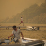 
              A man runs from smoke-engulfed Mazi area as wildfires rolled down the hill toward the seashore, in Bodrum, Mugla, Turkey, Sunday, Aug. 1, 2021. More than 100 wildfires have been brought under control in Turkey, according to officials. The forestry minister tweeted that five fires are continuing in the tourist destinations of Antalya and Mugla. (AP Photo/Emre Tazegul)
            