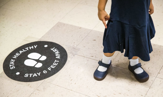 A student stands by a social distancing sign in the hallway of a Catholic elementary school in Broo...