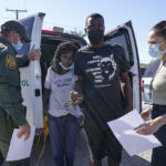 
              A U.S. Customs and Border Protection agent, left, drops off a migrant couple a member of of a humanitarian group, right, receives them after their release from custody, Friday, Sept. 24, 2021, in Del Rio, Texas. (AP Photo/Julio Cortez)
            