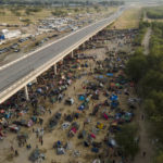 
              Migrants, many from Haiti, are seen at an encampment along the Del Rio International Bridge near the Rio Grande, Tuesday, Sept. 21, 2021, in Del Rio, Texas.  The options remaining for thousands of Haitian migrants straddling the Mexico-Texas border are narrowing as the United States government ramps up to an expected six expulsion flights to Haiti and Mexico began busing some away from the border.  (AP Photo/Julio Cortez)
            