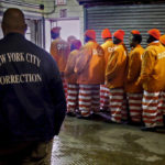
              FILE - In this March 16, 2011 file photo, a corrections official watches inmates file out of a prison bakery after working the morning shift at the Rikers Island jail in New York.  New York City’s notorious Rikers Island jail complex, troubled by years of neglect, has spiraled into turmoil during the coronavirus pandemic.  (AP Photo/Bebeto Matthews, File)
            