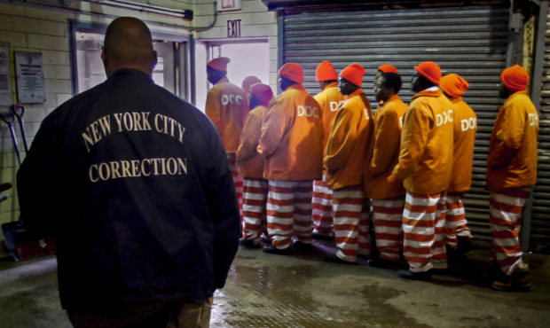 FILE - In this March 16, 2011 file photo, a corrections official watches inmates file out of a pris...