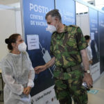 
              Rear Admiral Henrique Gouveia e Melo shares a joke with a military nurse during a visit to a vaccination center in Lisbon, Tuesday, Sept. 21, 2021. As Portugal nears its goal of fully vaccinating 85% of the population against COVID-19 in nine months, other countries want to know how it was able to accomplish the feat. A lot of the credit is going to Gouveia e Melo. (AP Photo/Armando Franca)
            